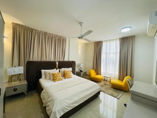 a bedroom with a bed and two yellow chairs at WAAFI LA CORNICHE RESIDENCE in Djibouti