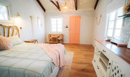 Lavender Lane Country Cottages في Kenilworth: غرفة نوم بسرير ومكتب ونوافذ