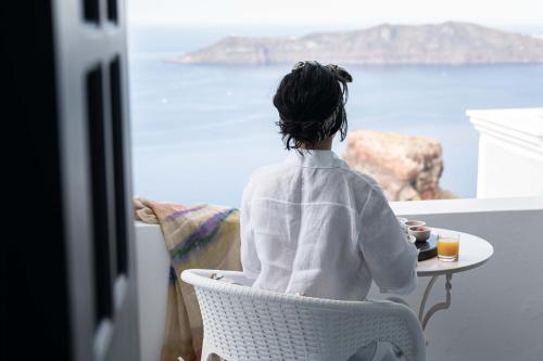 een vrouw aan een tafel die uitkijkt op de oceaan bij La Roka, Cliffside Memories in Imerovígli