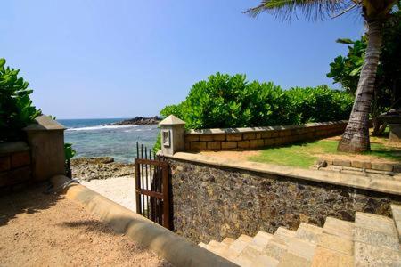 a stone wall with a gate next to the ocean at Villa Dhanu in Galle