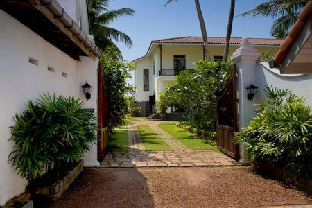 a house with a gate and a yard with palm trees at Villa Dhanu in Galle