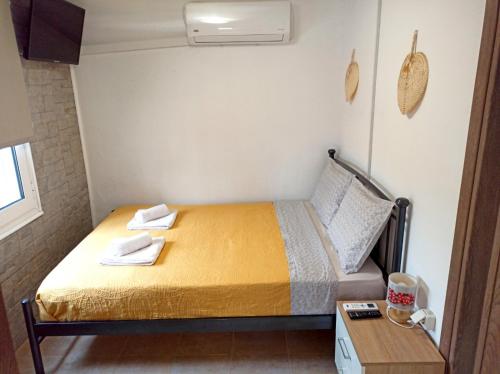 Un pequeño dormitorio con una cama con sábanas amarillas y una mesa. en Renovated Loft near the Center, en Heraclión
