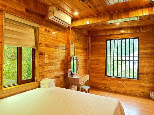 una camera da letto con pareti in legno, un letto e una finestra di Tam Coc Rocky Hotel a Ninh Binh
