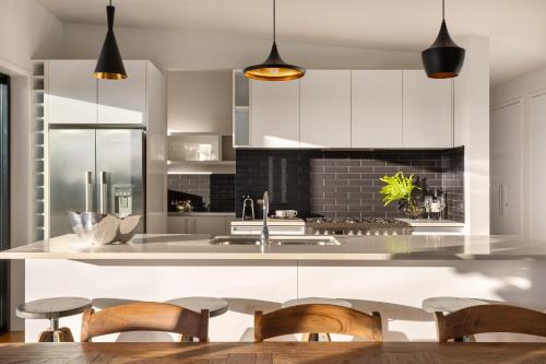 a kitchen with white cabinets and a table and chairs at Cable Bay Views in Oneroa