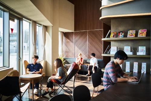 eine Gruppe von Menschen, die in einem Zimmer mit Laptops sitzen in der Unterkunft &AND HOSTEL HOMMACHI EAST in Osaka