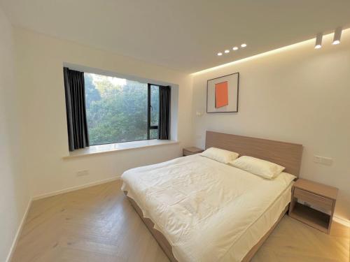 um quarto com uma cama grande e uma janela em Shanghai Jing'an Temple, Sunny Capital, Deluxe Three-Bedroom Apartment B&B, Extra Large Space em Xangai