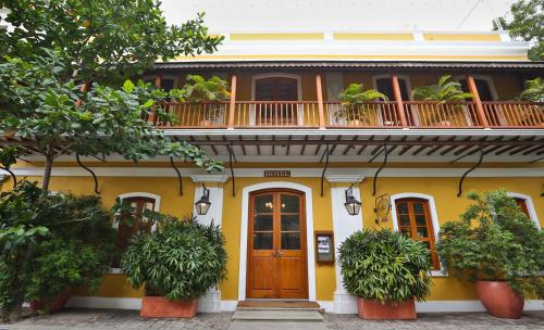 a yellow house with a balcony and a wooden door at Palais De Mahe - CGH Earth in Pondicherry