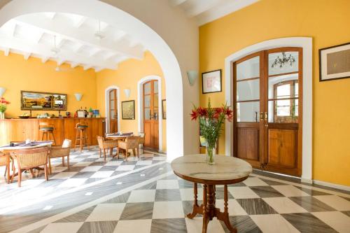 uma sala de estar com paredes amarelas e uma mesa com flores em Palais De Mahe - CGH Earth em Pondicherry