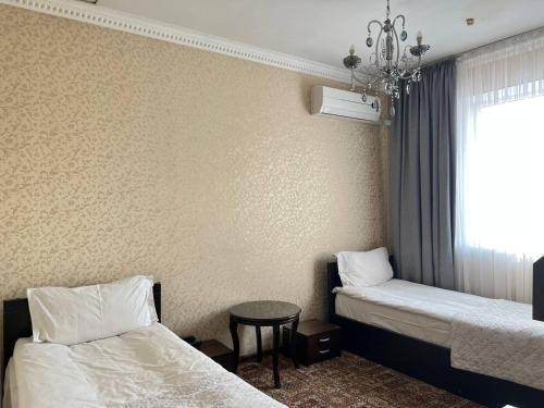 Pokój z 2 łóżkami, stołem i oknem w obiekcie Sultan w mieście Biszkek