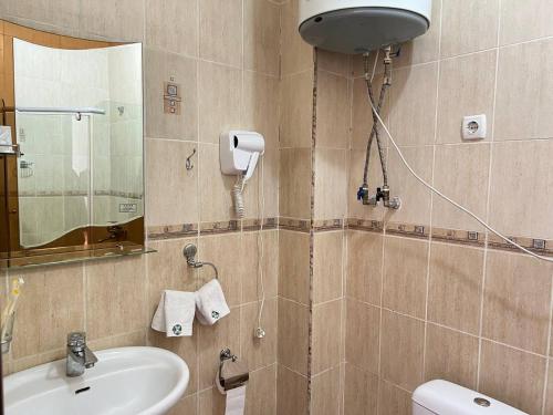 W łazience znajduje się umywalka, toaleta i lustro. w obiekcie Sultan w mieście Biszkek