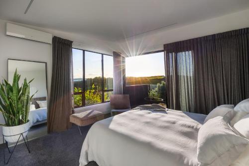 a bedroom with a large bed and a large window at Cable Bay Views in Oneroa