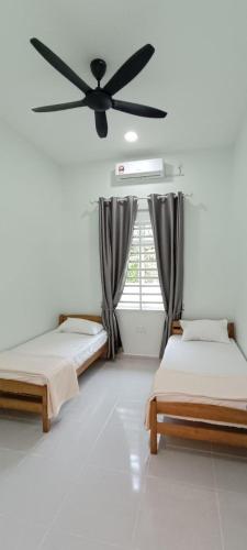 2 bedden in een kamer met een plafondventilator bij ISTANA VIEW HOMESTAY (Home C) in Kota Bharu