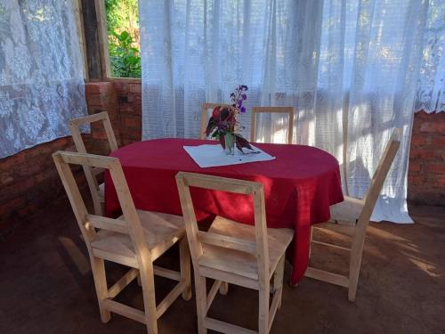 Lushoto的住宿－Irente Kinyonga Cottage，红色的桌子,椅子和花瓶