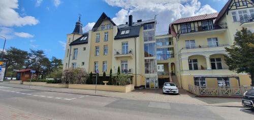 斯維諾烏伊希切的住宿－Villa Merry，停在黄色建筑前面的白色汽车