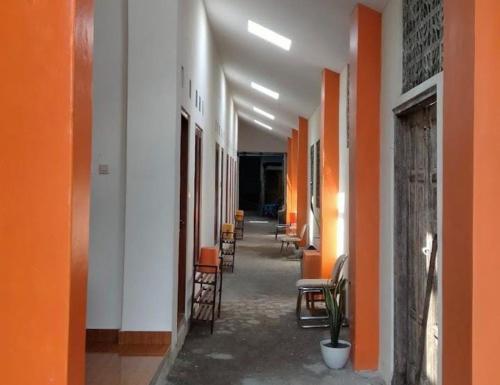 een lege hal met oranje en witte muren en stoelen bij Homestay Syariah Bantul in Bantul