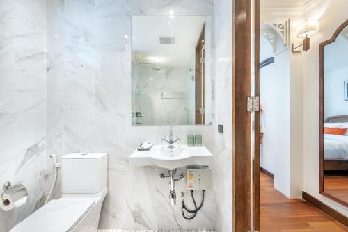 a bathroom with a sink and a toilet and a mirror at Cherie Bangkok Boutique Hotel in Bangkok