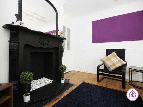 a living room with a fireplace and a chair at Cowbridge House, Huge Monthly Discounts, Contractors in Cardiff