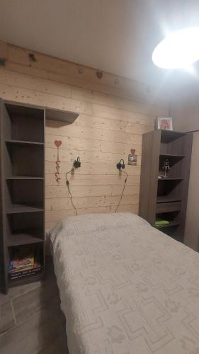 een slaapkamer met een bed en een houten muur bij Villa de la dore in Le Mont-Dore