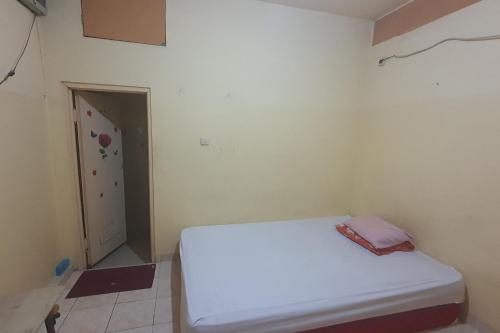 ein Schlafzimmer mit einem weißen Bett in einem Zimmer in der Unterkunft OYO 93895 Koh Wat Homestay Syariah in Plosobegem