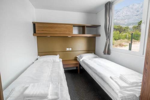 dwa łóżka w pokoju z oknem w obiekcie SUNNY Mobile Homes Bijela Uvala w Poreču