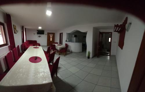 a dining room with a long table and red chairs at La Marian pensiune restaurant in Munună