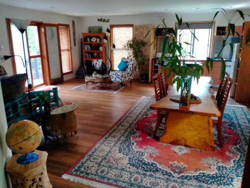 sala de estar con mesa y planta en Cosy Romantic Cottage, en Tallebudgera