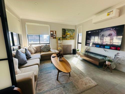 a living room with a couch and a table at A Private Ensuite with AC and TV in Austral