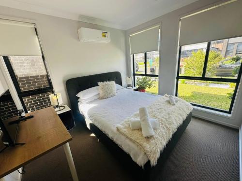 1 dormitorio con 1 cama con sábanas blancas y ventanas en A Private Ensuite with AC and TV en Austral