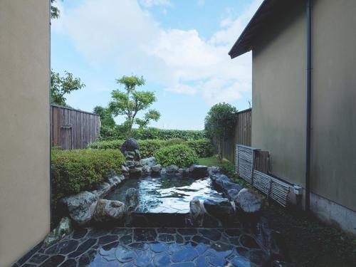 a small pond in a yard next to a building at Hanare Yado Yoshizumi in Izu