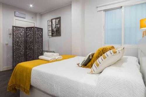 a bedroom with a large white bed with yellow sheets at Modern flat in the city center - Madrid SEG in Madrid