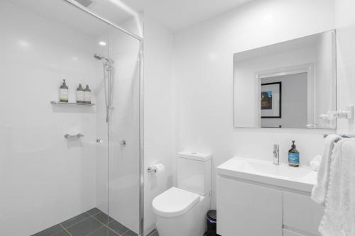 a white bathroom with a toilet and a shower at The Beach Apartment in Huskisson