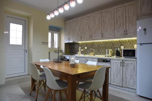 a kitchen with a wooden table and white chairs at Villa Maxim in Corfu Town in Anemómylos