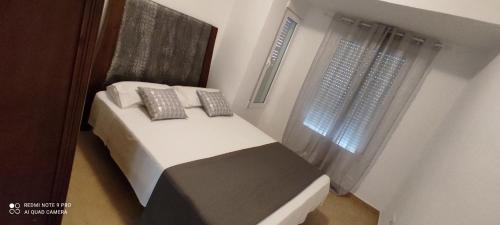 a bedroom with a bed with two pillows and a window at TU CASA en Benetússer , VALENCIA in Benetúser