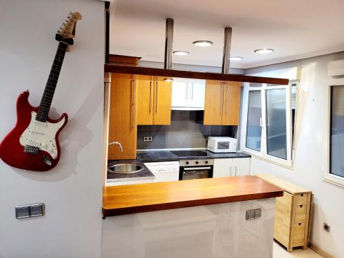 uma cozinha com uma guitarra pendurada na parede em Apto Cimavilla. Wifi gratuito. VUT-827-AS em Gijón