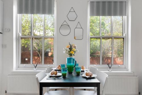 a dining room with a table and chairs and windows at Old Street Apartments By Morethanstays in London