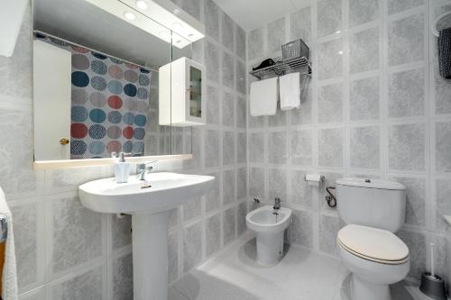 a white bathroom with a toilet and a sink at Casa García in L'Aldea