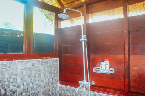 a shower in a bathroom with a wooden wall at Mentawai Ebay Playground Surfcamp in Masokut