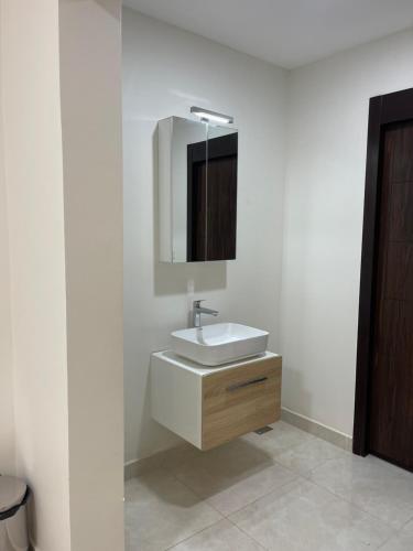 La salle de bains blanche est pourvue d'un lavabo et d'un miroir. dans l'établissement WAAFI CITY CENTER RESIDENCE, à Djibouti