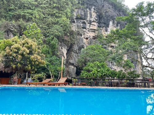 a blue swimming pool with a mountain in the background at Tam Coc Rocky Hotel in Ninh Binh