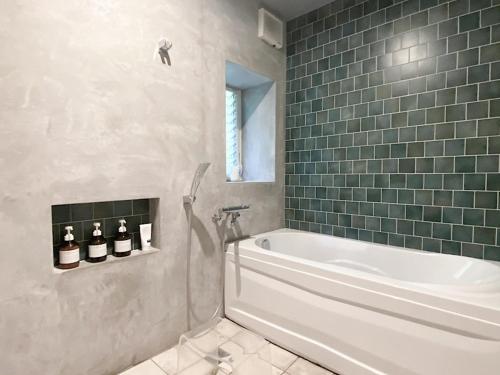 a bathroom with a white tub and green tiles at Nonoya - Vacation STAY 78469v in Goto