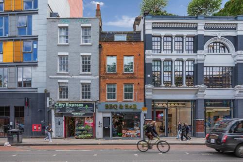 a man riding a bike down a street with buildings at Old Street Apartments By Morethanstays in London