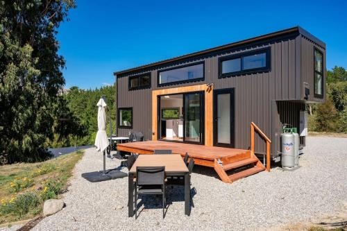 ein winziges Haus mit einem Picknicktisch und einer Bank in der Unterkunft Tiny Home on 1 Acre Land in Picturesque Hawea Flat in Hawea Flat