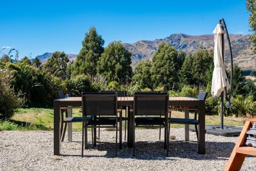 a wooden table with chairs and an umbrella at Tiny Home on 1 Acre Land in Picturesque Hawea Flat in Hawea Flat