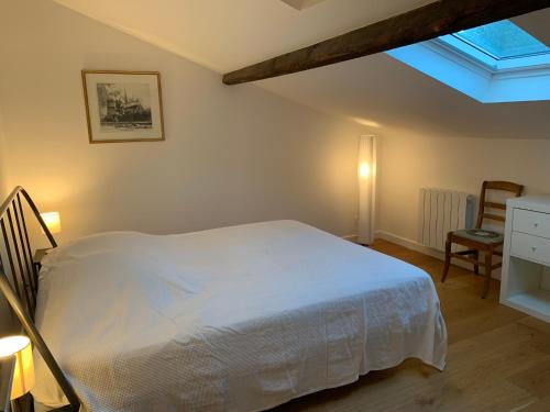 een slaapkamer met een wit bed en een dakraam bij L'Atelier - Boulogne - Roland Garros, Parc des Princes, JO in Boulogne-Billancourt