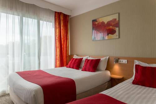 a hotel room with two beds and a window at The Originals City, Hôtel Villancourt, Grenoble Sud in Le Pont-de-Claix