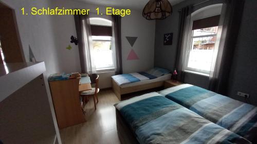 a bedroom with a bed and a desk and two windows at Ferienwohnung Rüfflerstub in Eibenstock
