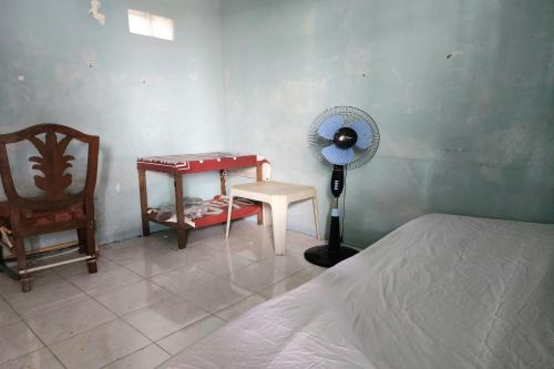 a bedroom with a bed and a desk and a fan at SPOT ON 93894 Jamil Homestay Syariah in Plosobegem