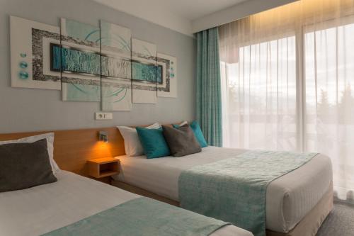 a hotel room with two beds and a window at The Originals City, Hôtel Villancourt, Grenoble Sud in Le Pont-de-Claix