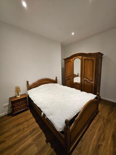 a bedroom with a large bed and a wooden cabinet at appartement des jeux in Chaource