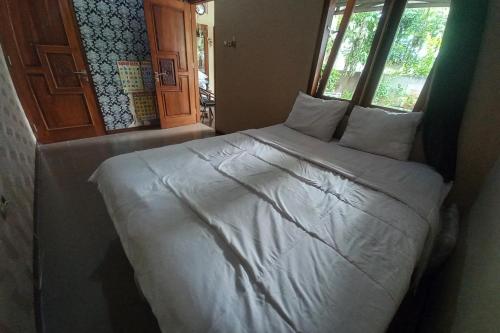 a bed with white sheets and pillows in a room at OYO 93892 Homestay Koe Syariah in Purwokerto